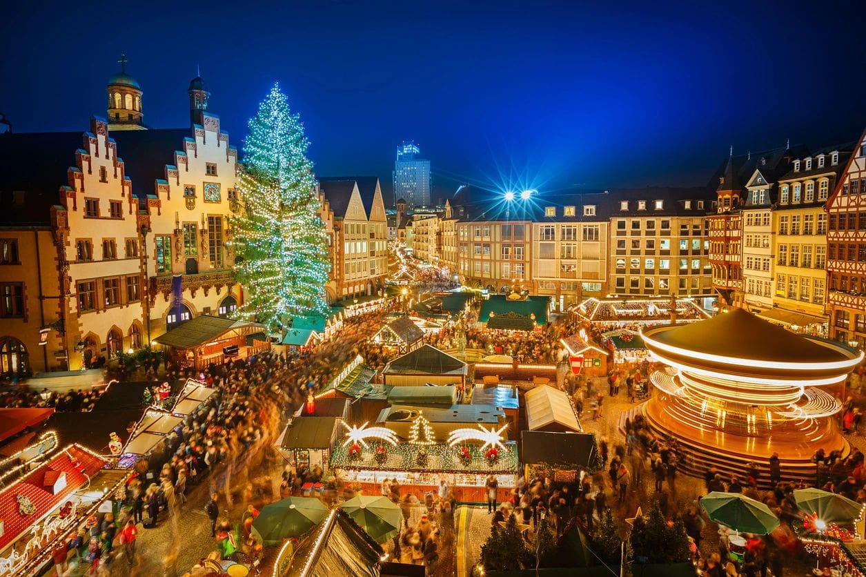 A christmas market with people and tents in the background.