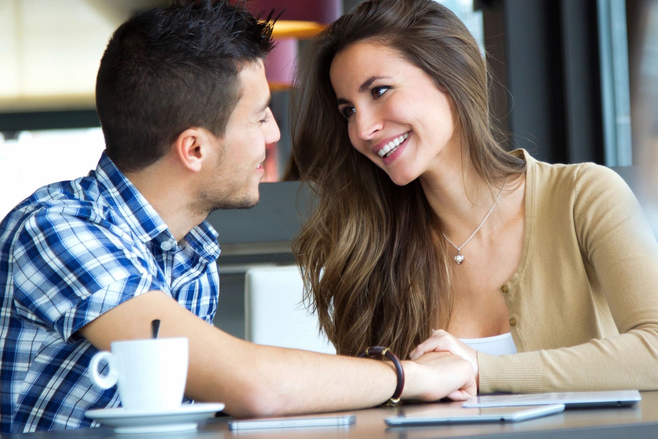 A man and woman sitting at a table with coffee.