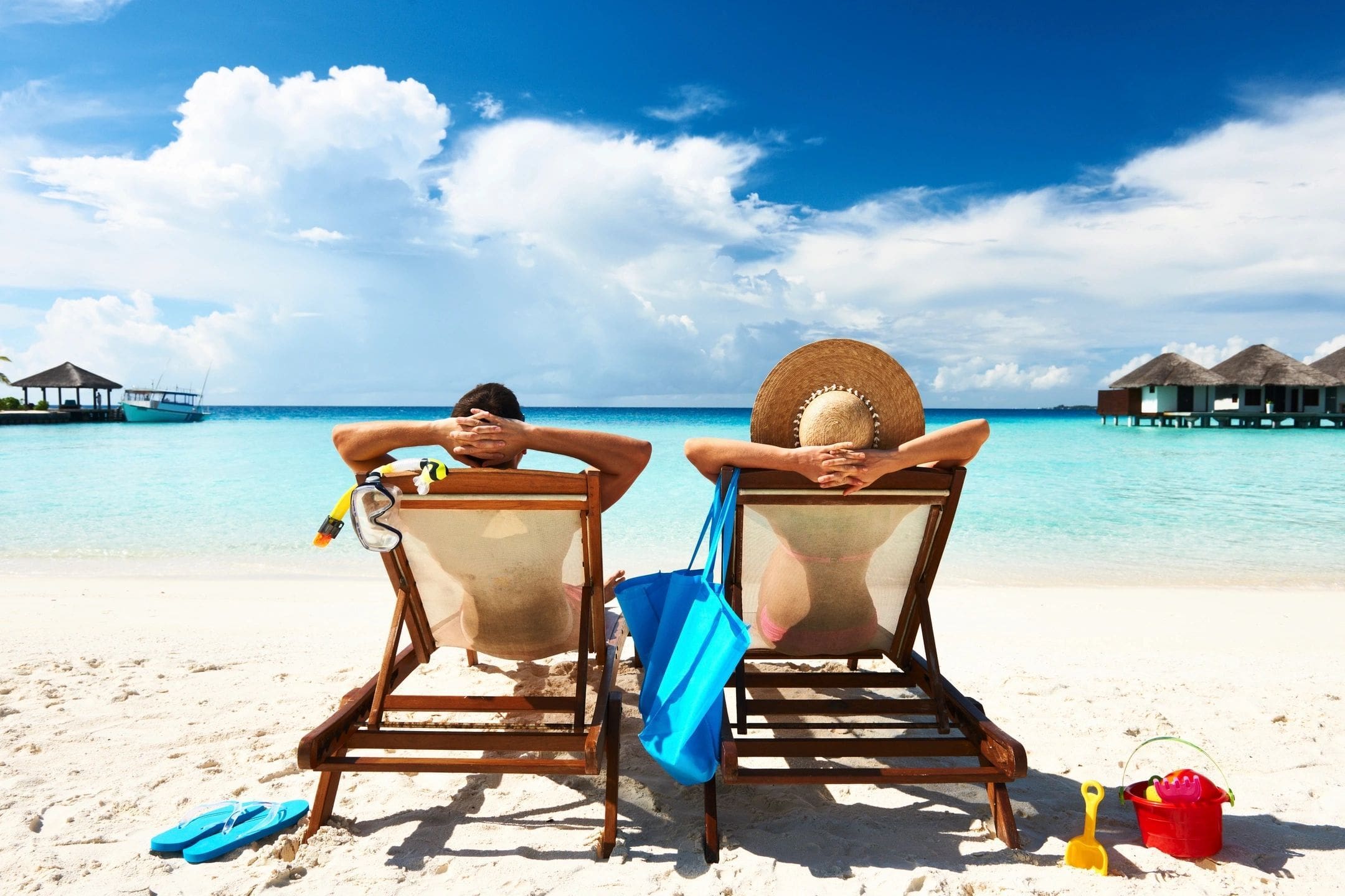 Two people sitting in lawn chairs on the beach